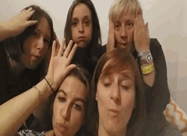a group of people making funny faces with their hands on their heads .