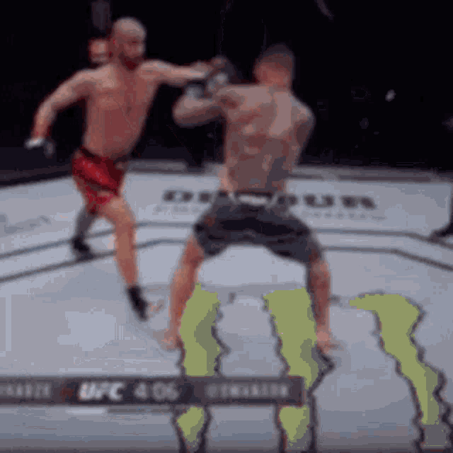two men are fighting in a boxing ring with a monster logo in the background .