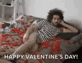 a man is laying on a bed covered in red petals and hearts .