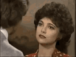 a woman with a big afro is looking at a man in a suit .