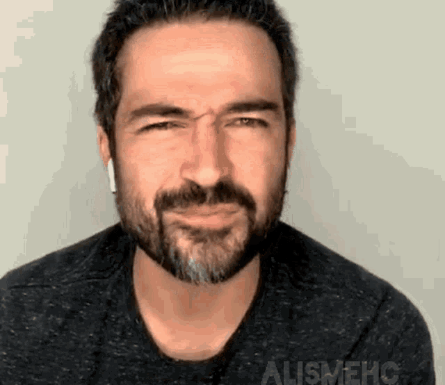 a man with a beard is making a funny face while wearing ear buds .
