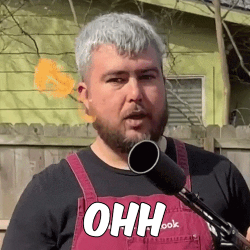 a man with a beard and overalls is holding a microphone and says ohh