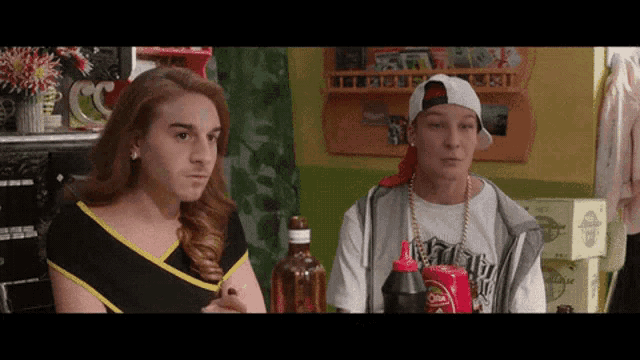 a man and a woman are sitting at a table with a bottle of ketchup