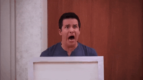 a man is holding a painting in front of his face and making a surprised face .
