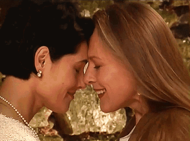 two women are touching their foreheads with their eyes closed