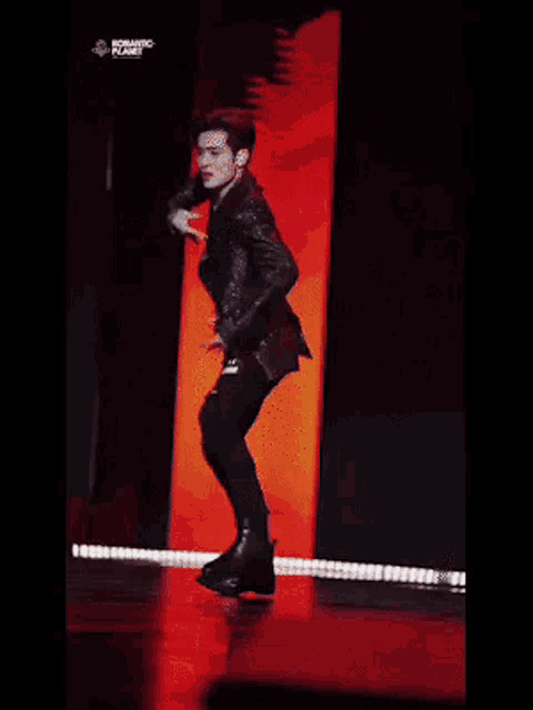 a man is dancing on a stage in front of a red wall .