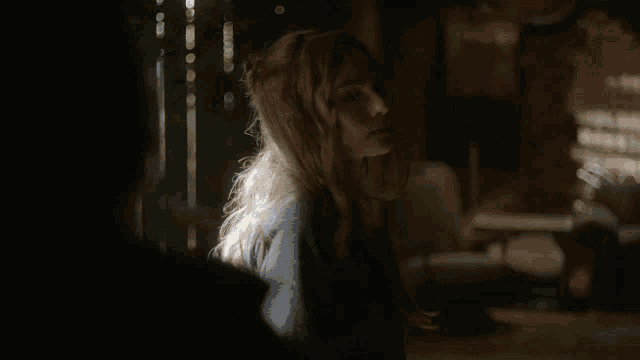 a woman is standing in a dark room with the sun shining on her face