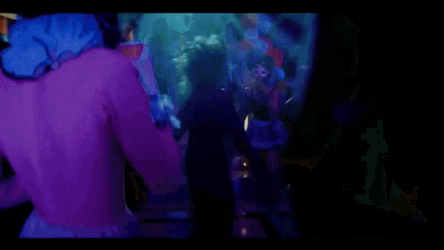 a crowd of people are dancing in a dark room with purple lights