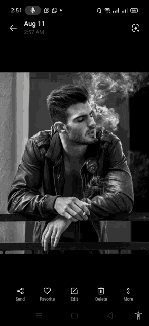 a man in a leather jacket is smoking a cigarette while leaning on a railing .