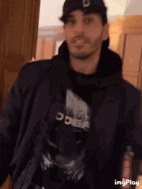 a man wearing a black hat and a black jacket is standing in a room .