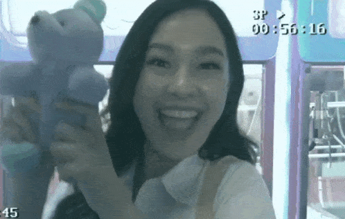 a woman is holding a teddy bear in front of a timer that reads 00:56:16