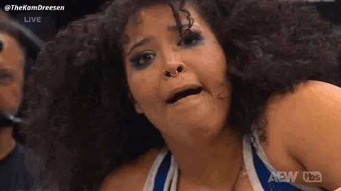 a woman with curly hair is making a funny face on a wrestling show .