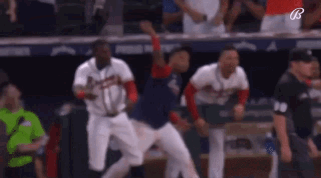 a group of baseball players are jumping in the air in a dugout .
