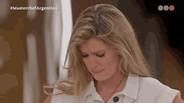 a woman in a white shirt is crying in front of a masterchef argentina logo