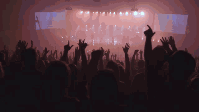 a crowd of people are raising their hands in the air at a concert