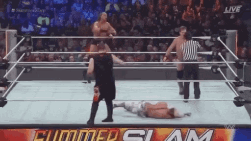 a man is laying on the ground in a wrestling ring while a referee watches .