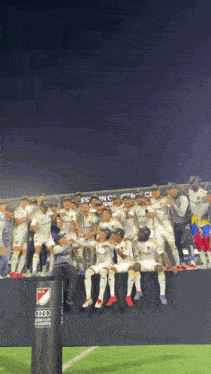a group of soccer players are posing for a picture in front of a sign that says audi