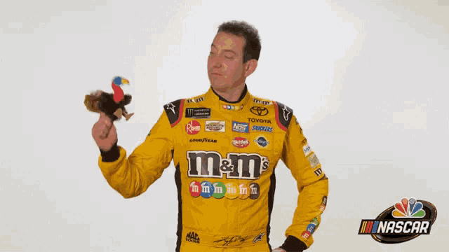 a man in a yellow m & m 's shirt holds a stuffed animal