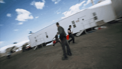 a blurred image of people walking in front of a trailer that says ' emergency ' on it