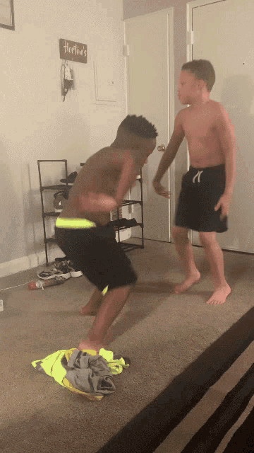 two boys are playing in a living room with a sign that says hartmut 's on the wall