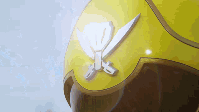 a close up of a yellow helmet with a sword on it