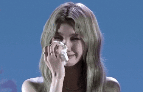 a woman with green hair is crying and holding a napkin to her face .