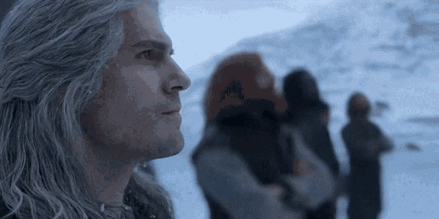 a man with gray hair is standing in front of a group of people standing in the snow .