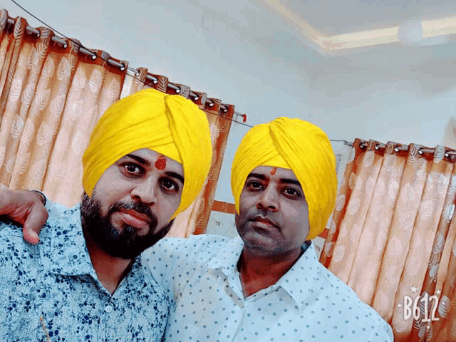 two men wearing yellow turbans pose for a photo with b612 written on the bottom right