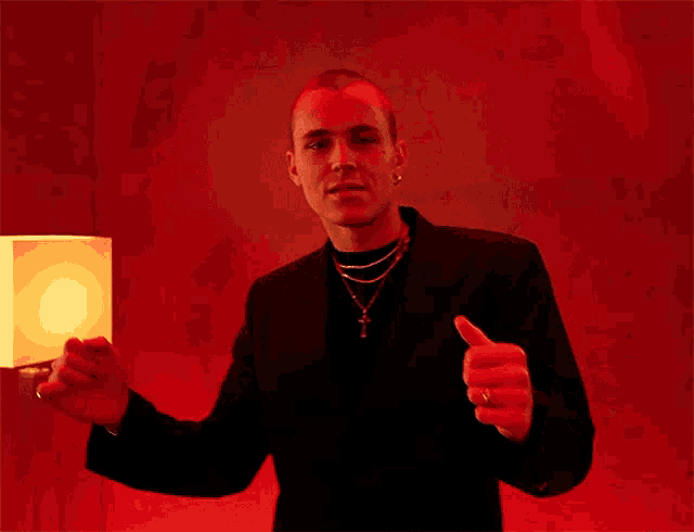 a man giving a thumbs up in front of a lamp