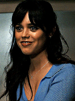 a close up of a woman wearing a blue sweater and necklace