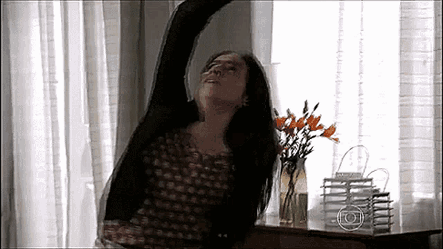 a woman is stretching her arm in front of a window