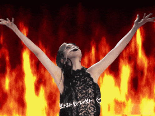 a woman with her arms outstretched in front of fire