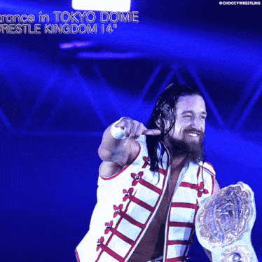 a wrestler is holding a world heavyweight championship while pointing at the camera
