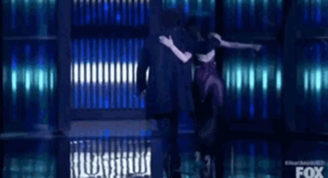 a man and a woman are dancing on a stage with a fox logo in the background