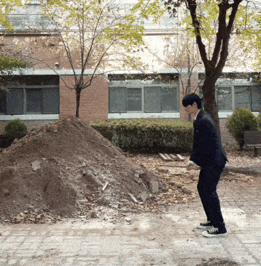 a man in a suit is standing in front of a large pile of dirt
