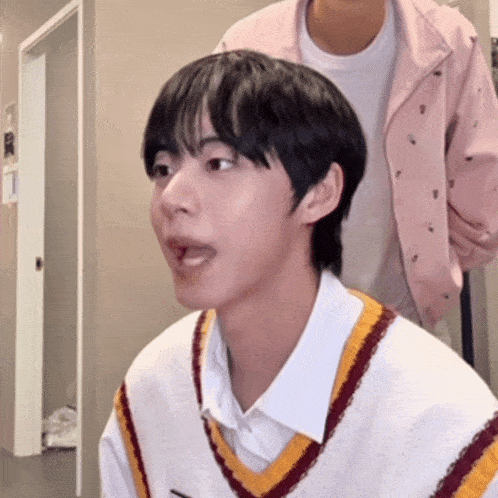 a young man wearing a white shirt and a striped vest is making a funny face