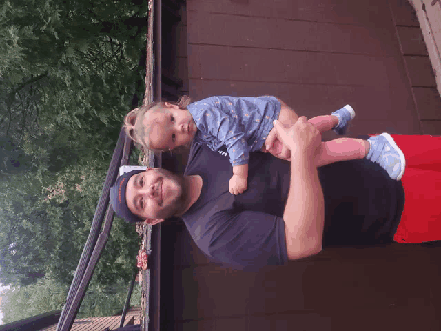 a man holding a baby wearing a black shirt that says ' i love ny ' on it