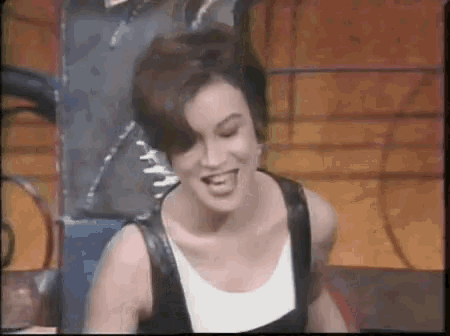 a woman with short hair is smiling and wearing a black and white tank top