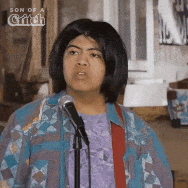 a man in a wig is singing into a microphone in front of a sign that says son of a bitch