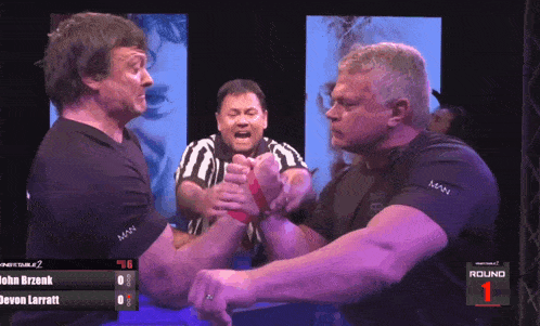 two men arm wrestling in front of a screen that says round one