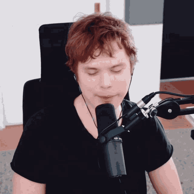 a man in a black shirt is sitting in front of a microphone