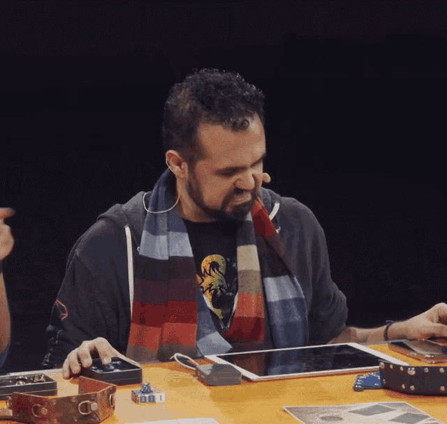 a man wearing a scarf looks at a tablet