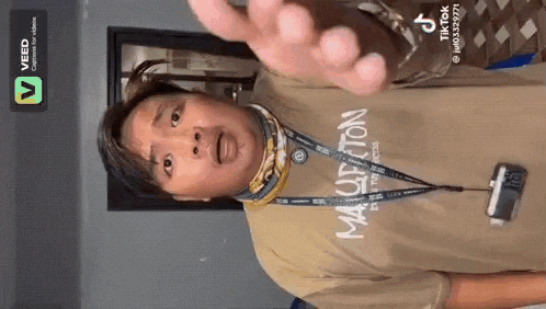 a man wearing a t-shirt and a lanyard is making a funny face .