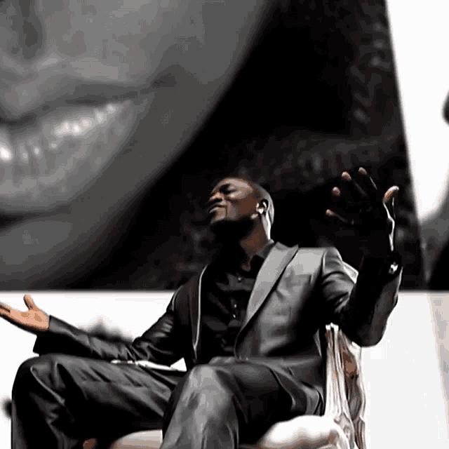 a man in a suit is sitting in a chair with his hands outstretched