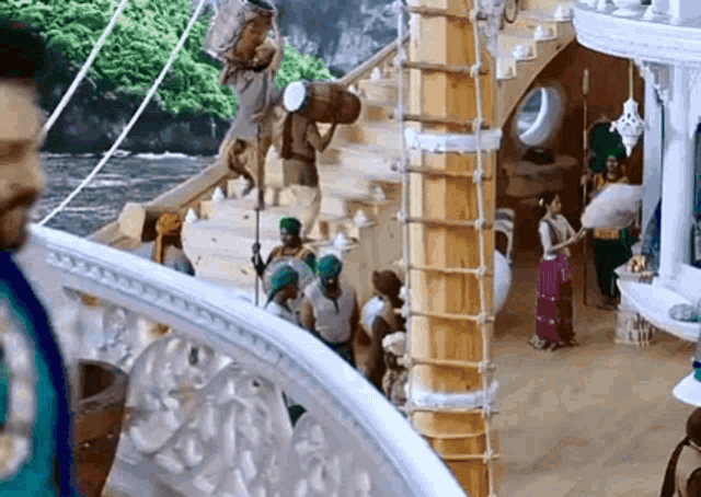a man is standing on a balcony looking out over a boat with people on it .