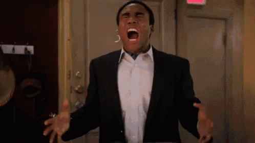 a man in a suit and tie is screaming with his mouth open in front of an exit sign .