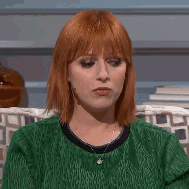 a woman with red hair is wearing a green shirt