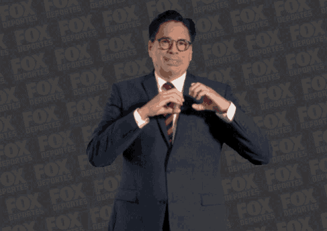 a man in a suit and tie is standing in front of a fox logo