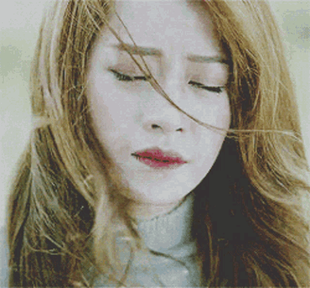 a woman with her eyes closed and her hair blowing in the wind