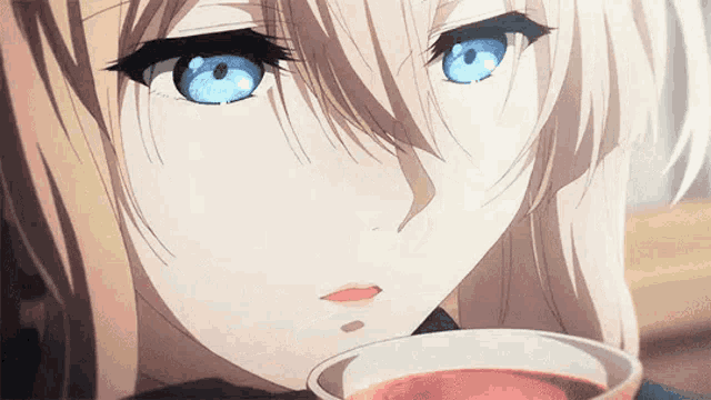 a close up of a girl with blue eyes drinking from a cup of tea .